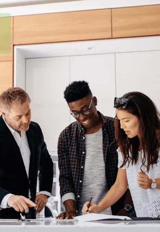 A couple going through paperwork with their broker at a kitchen bench