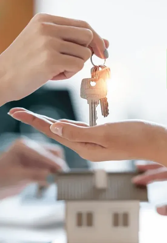 Keys being placed into an open hand above a model house